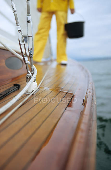 Imagem cortada do homem de pé no convés do barco segurando balde — Fotografia de Stock