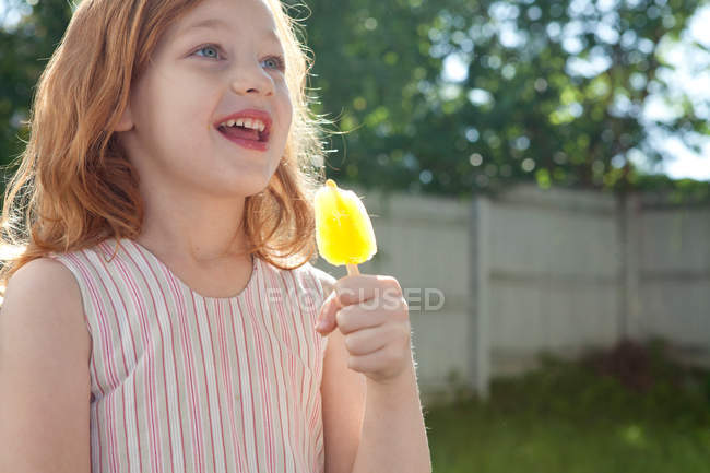 Portrait of Girl holding ice lolly outdoors — Stock Photo