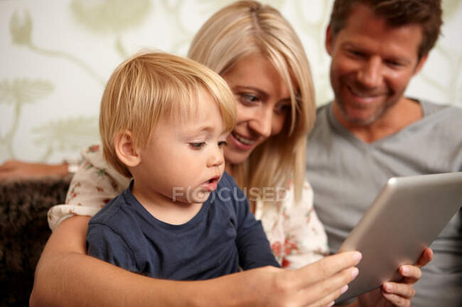 Padre, madre e hijo usando tableta digital - foto de stock