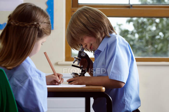 Crianças em idade escolar que trabalham em uma tarefa em sala de aula — Fotografia de Stock