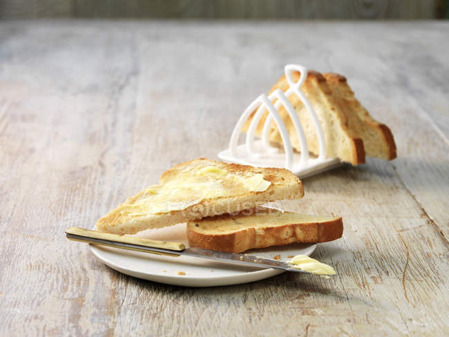 Weißbrot in Scheiben geschnitten mit Butter auf Teller mit Messer — Stockfoto