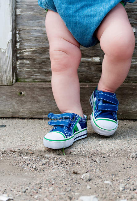 Pernas de uma criança que usa sapatos de treino — Fotografia de Stock
