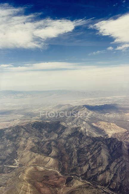 Aerial view of rocky mountains under blue cloudy sky — Stock Photo