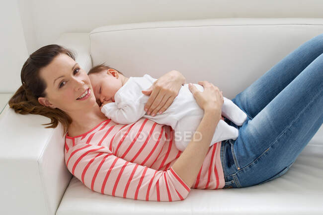 Mujer y niña descansando en el sofá - foto de stock