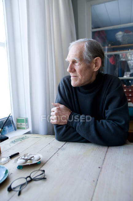Senior man looking out of window — Stock Photo