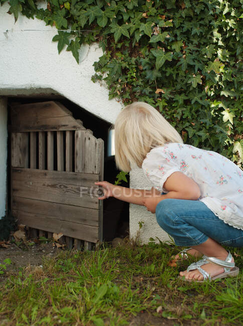 Young girl peering into wooden door — Stock Photo