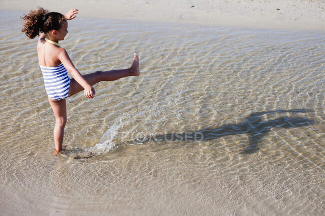 Молодая девушка играет в воду на пляже — стоковое фото