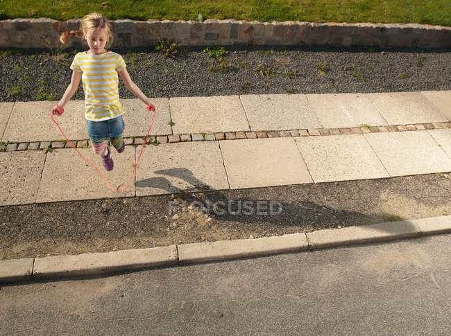 Young girl skipping on sidewalk — Stock Photo