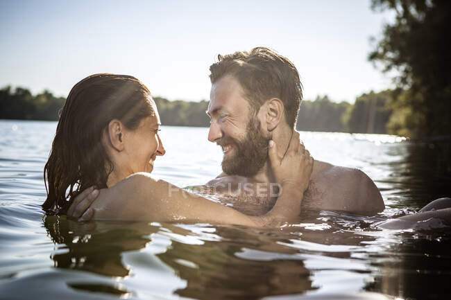 Paar von Angesicht zu Angesicht umarmt, lächelnd im Wasser, Berlin, Deutschland — Stockfoto