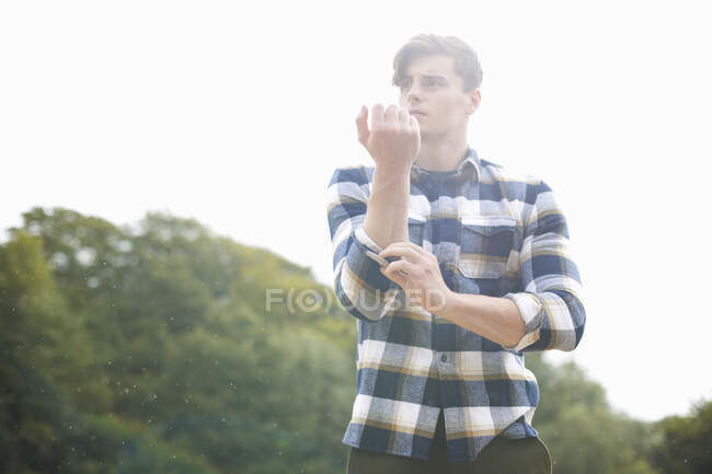 Portrait of man wearing plaid shirt rolling up sleeves — Stock Photo