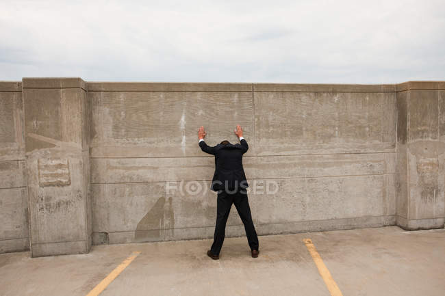 Businessman standing with hands against wall — Stock Photo