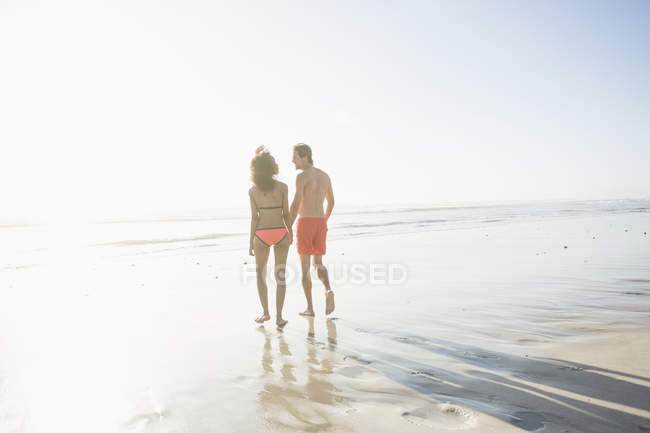 Вид на молодую пару в купальниках на пляже с солнечным освещением, Кейптаун, Западный Кейп, Южная Африка — стоковое фото