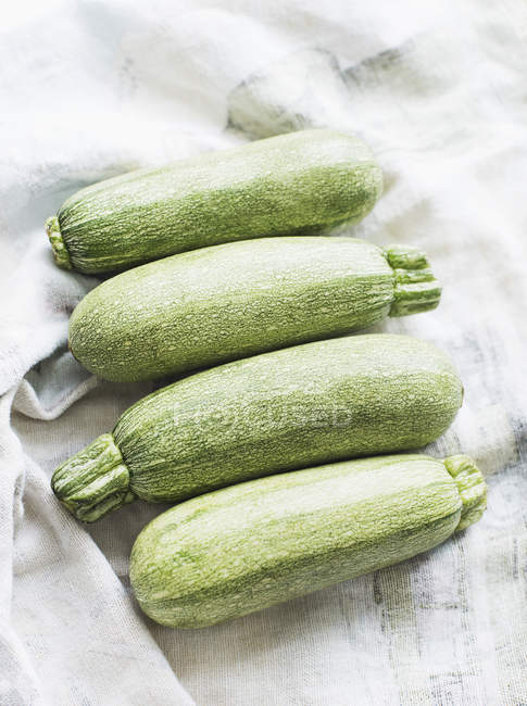 Primo piano di quattro zucchine fresche poste in fila — Foto stock