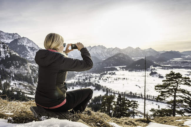 Joven excursionista fotografiando Allgau Alps en smartphone, Baviera, Alemania - foto de stock