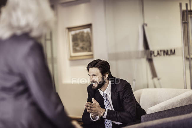 Бизнесмен, сидящий в кресле и разговаривающий с бизнесвумен — стоковое фото