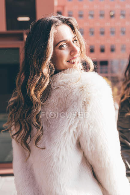 Portrait of young woman, looking over shoulder, smiling — Stock Photo