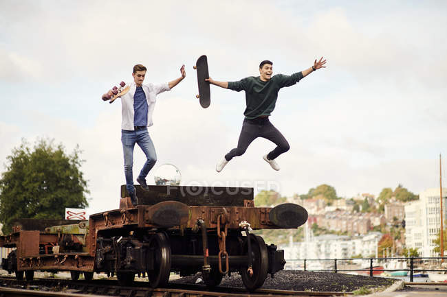 Два молодых человека выпрыгивают из трейлера на железнодорожном пути, Бристоль, Великобритания — стоковое фото