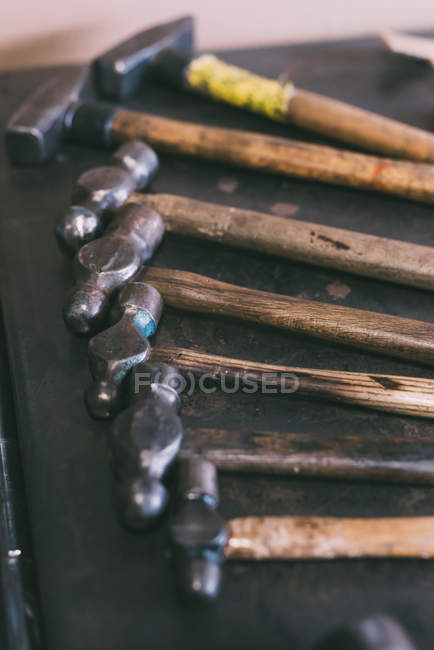 Fila de martillos colocados en el banco de trabajo de forja - foto de stock