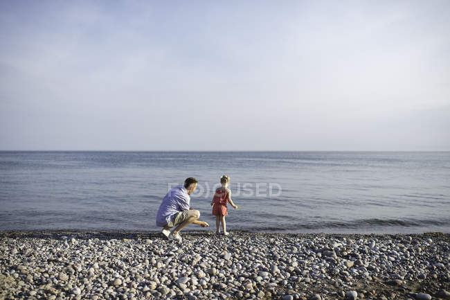 Hombre adulto y su hija robando piedras en el Lago Ontario, Oshawa, Canadá - foto de stock