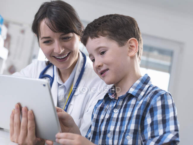 Médico y niño usando tableta digital - foto de stock
