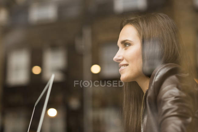 Vista da janela de jovem empresária com laptop no café — Fotografia de Stock