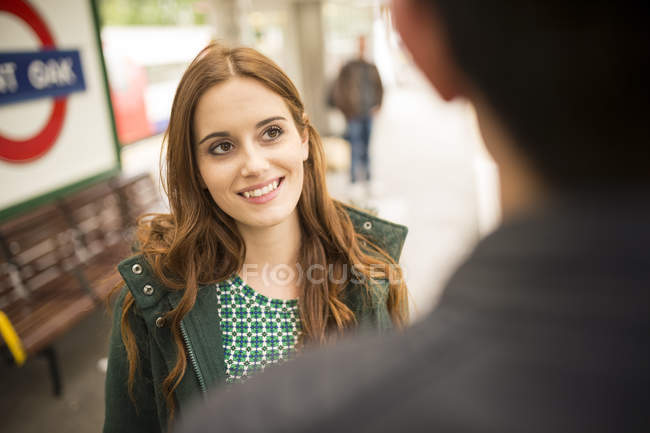 Жінка на залізничній платформі дивиться на друга посміхається — стокове фото