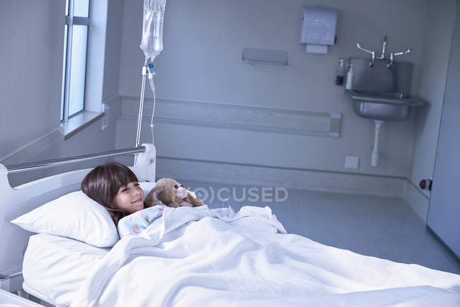 Ragazza paziente a letto abbraccio giocattolo coniglio in ospedale reparto bambini — Foto stock