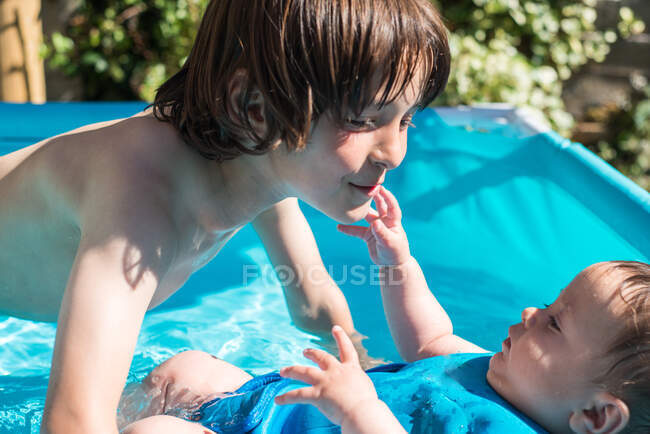 Irmãos felizes que jogam na piscina inflável no dia de verão — Fotografia de Stock