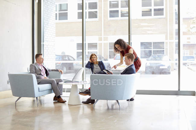 Mulheres de negócios e homens que se reúnem em sofás de escritório — Fotografia de Stock