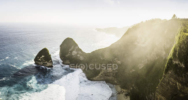 Vista soleada de la formación de rocas y la costa con olas de surf - foto de stock
