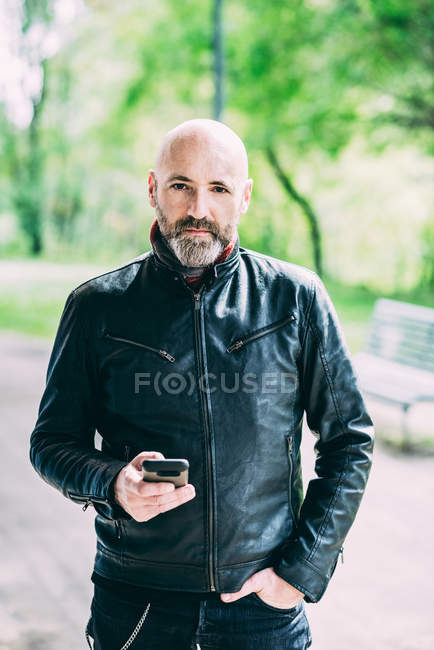 Retrato de motociclista masculino maduro segurando smartphone — Fotografia de Stock