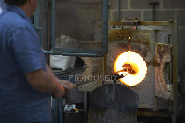 Male caucasian Glassblower in workshop using furnace — Stock Photo