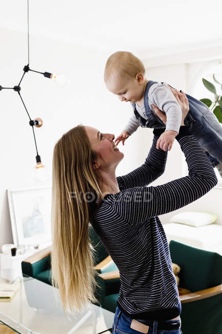 Mujer sosteniendo bebé hija en sala de estar - foto de stock
