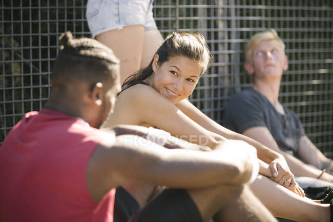 Four adult friends sitting chatting on basketball court — Stock Photo