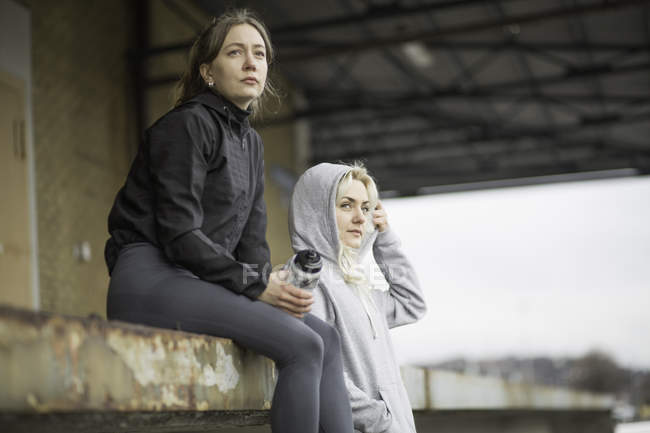 Two female runner friends looking out from warehouse platform — Stock Photo