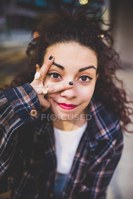 Portrait de femme regardant la caméra à travers les doigts — Photo de stock