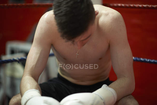 Boxeador sentado en la esquina del ring de boxeo, agotado - foto de stock