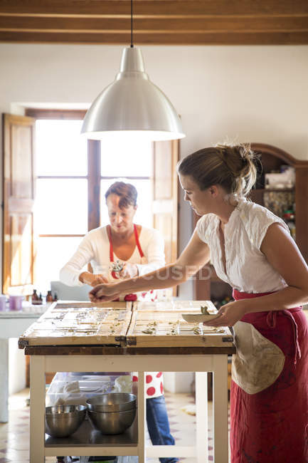 Молодая женщина наносит сушеную лаванду на мыло в мыльной мастерской ручной работы — стоковое фото