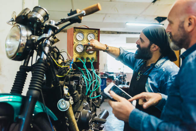 Dois homens maduros, trabalhando em motocicleta na garagem — Fotografia de Stock