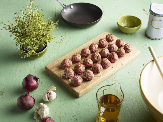 Rows of raw prepared greek meatballs on chopping board — Stock Photo