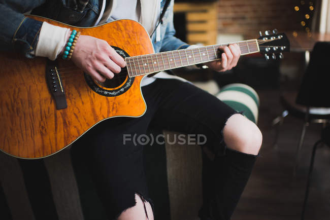 Молодий чоловік вдома, грає на гітарі, середня секція — стокове фото