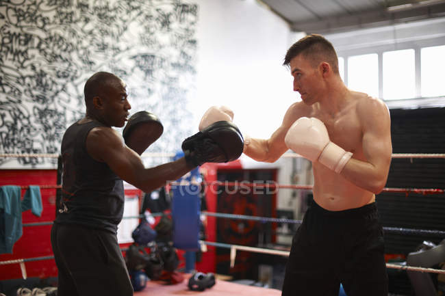 Boxer in allenamento con allenatore sul ring di boxe — Foto stock