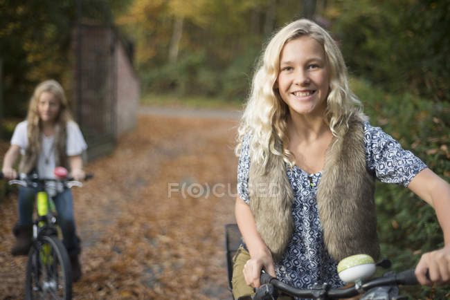 Retrato de duas irmãs pedalando no parque de outono — Fotografia de Stock