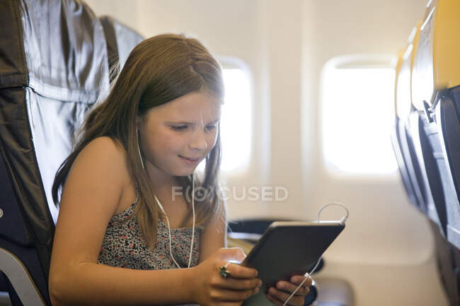 Молодая девушка с цифровым планшетом в самолете — стоковое фото