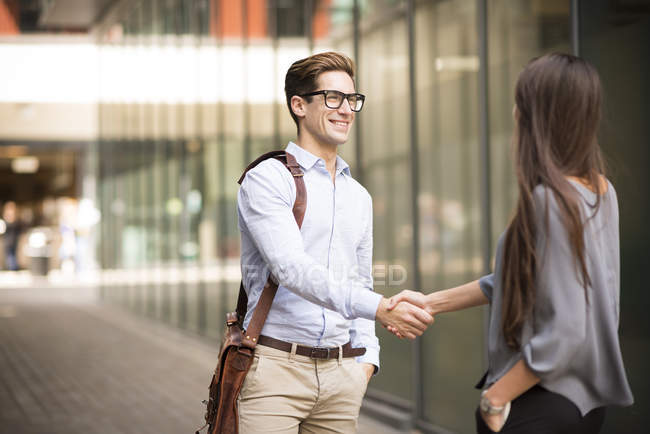 Businessman and woman shaking hands outside office, London, UK — Stock Photo