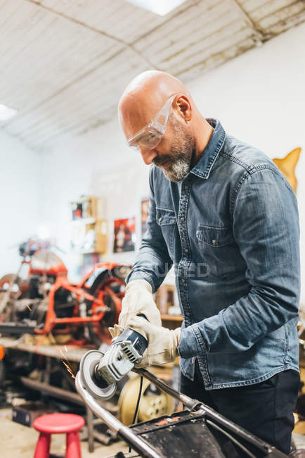 Hombre maduro, trabajando en moto en garaje - foto de stock