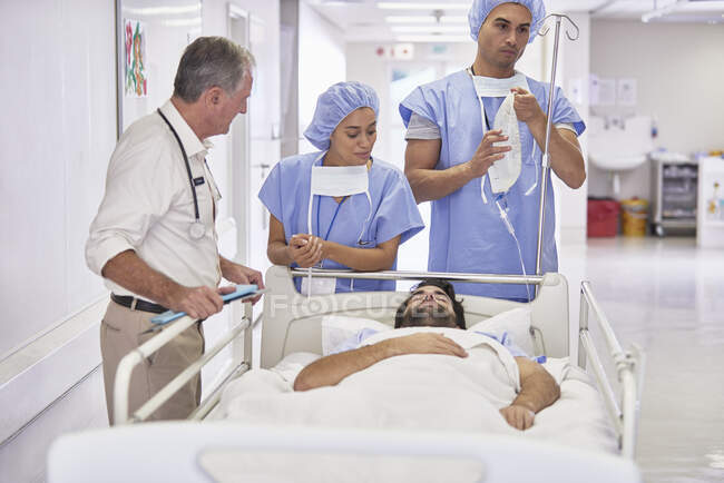 Médecins entourant le patient dans le lit d'hôpital — Photo de stock