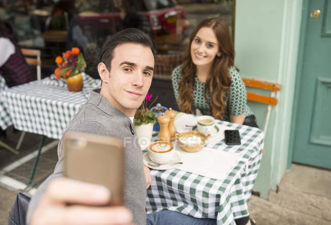 Пара в кафе на тротуаре разговаривает селфи — стоковое фото