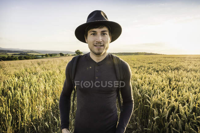 Retrato del hombre de sombrero de pie en el campo - foto de stock