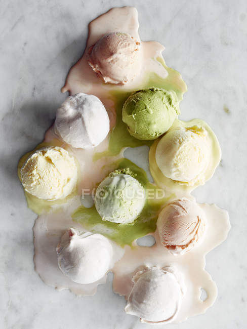 Scoops of ice cream melting on marble surface — Stock Photo